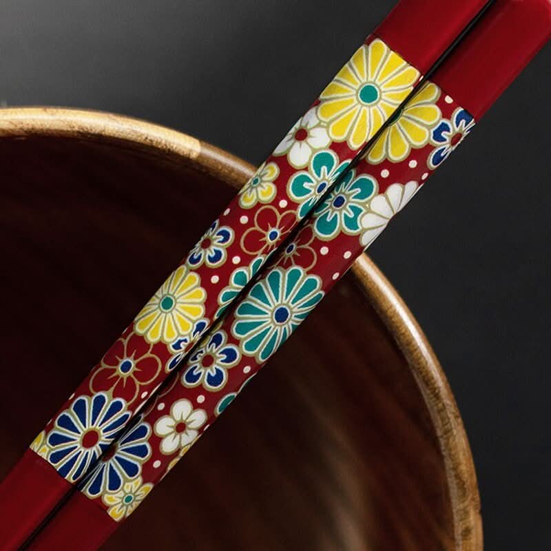 Red, floral patterned Kutani-Yaki natural wooden chopsticks in a wooden bowl.
